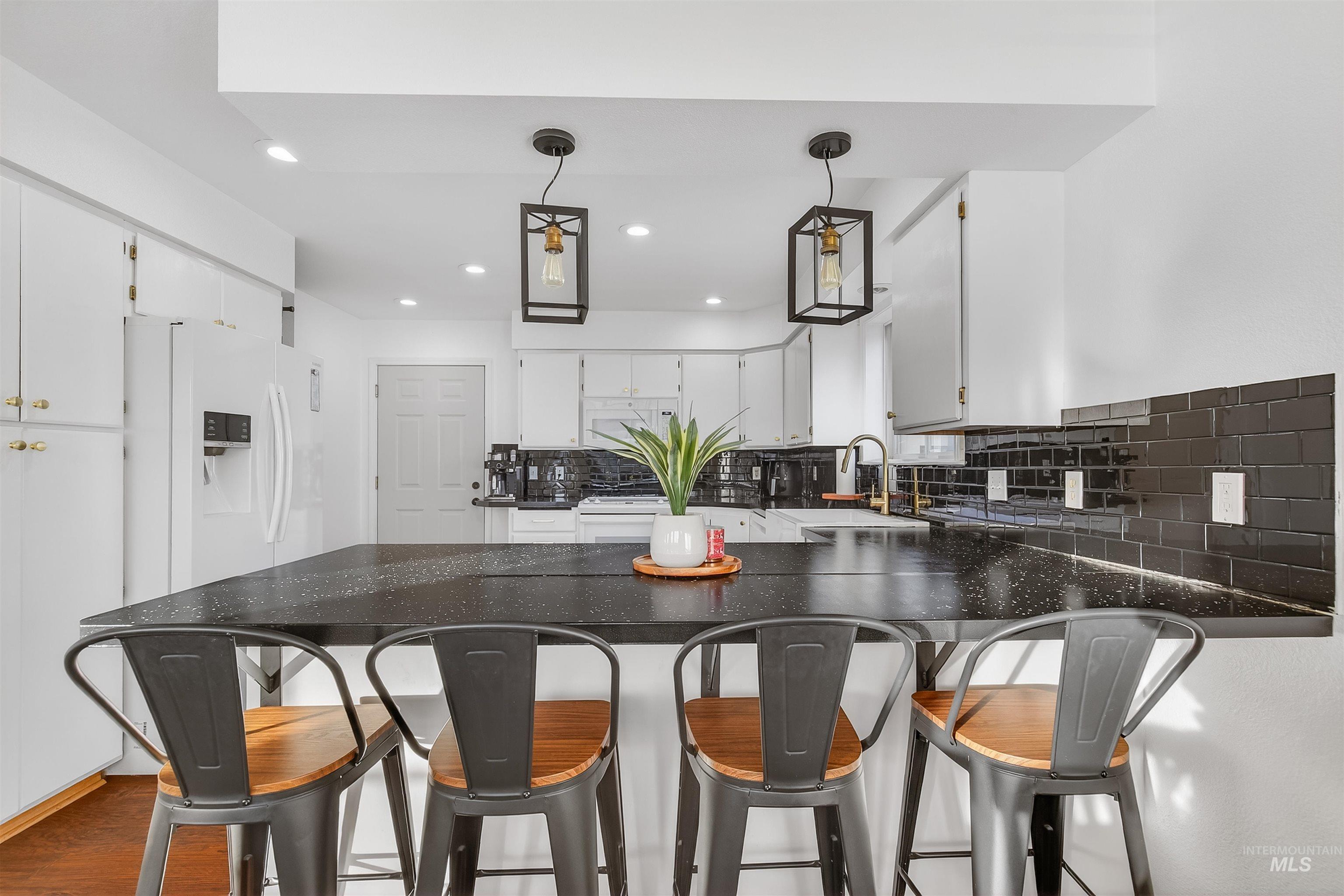 822 15th Avenue Lewiston, ID 83501 - Photo 14 of 44 Kitchen with decorative light fixtures, a peninsula, white cabinetry, white refrigerator with ice dispenser, and tasteful backsplash