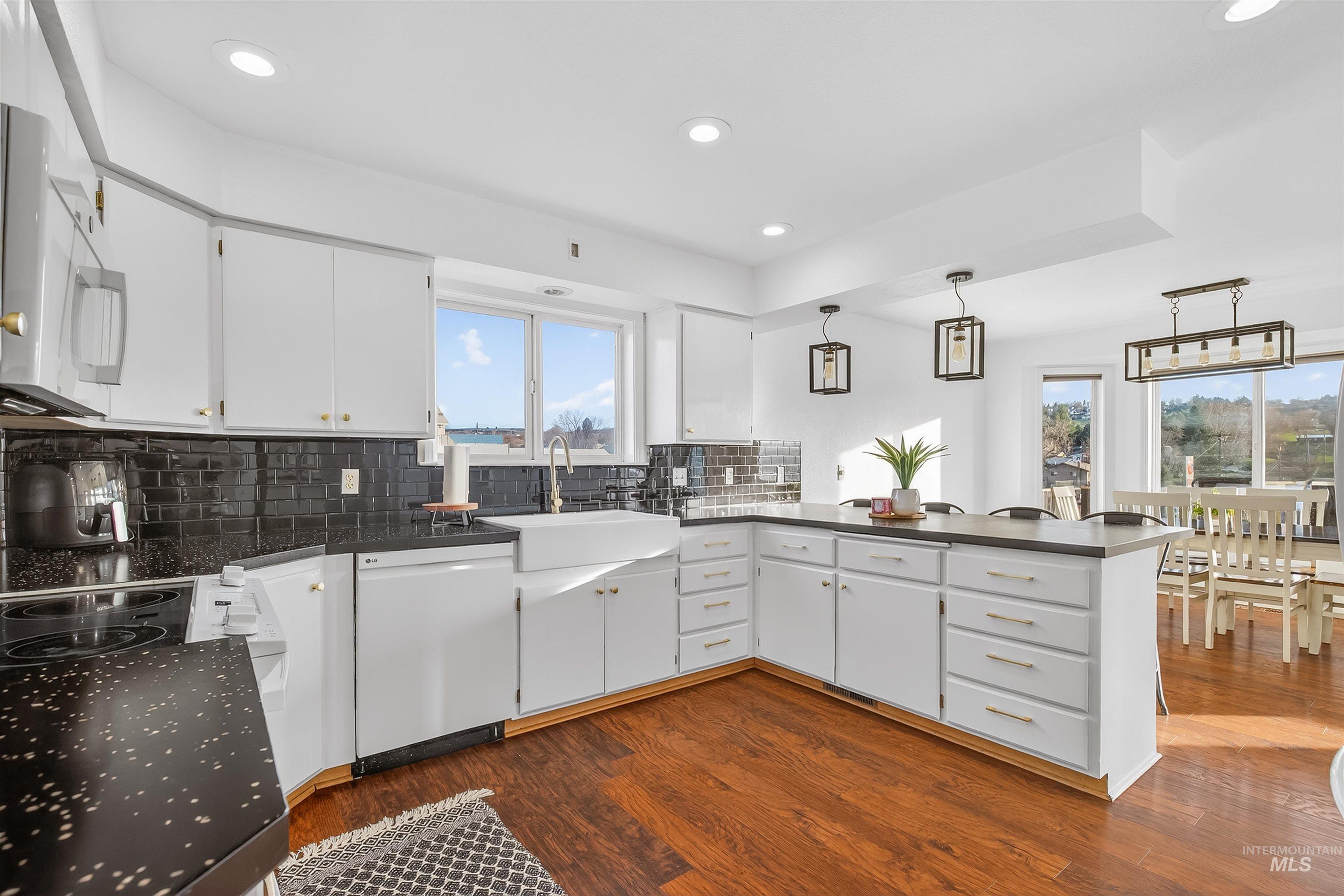822 15th Avenue Lewiston, ID 83501 - Photo 16 of 44 Kitchen featuring white cabinets, a peninsula, pendant lighting, dark countertops, and white appliances