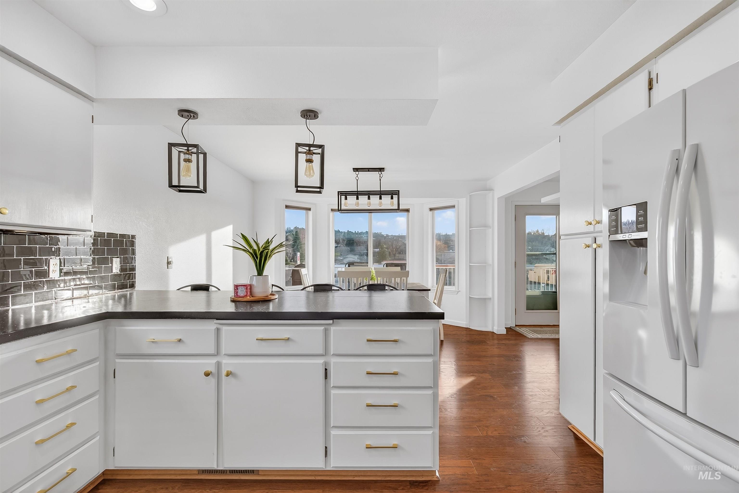 822 15th Avenue Lewiston, ID 83501 - Photo 17 of 44 Kitchen with a peninsula, white refrigerator with ice dispenser, white cabinets, tasteful backsplash, and decorative light fixtures