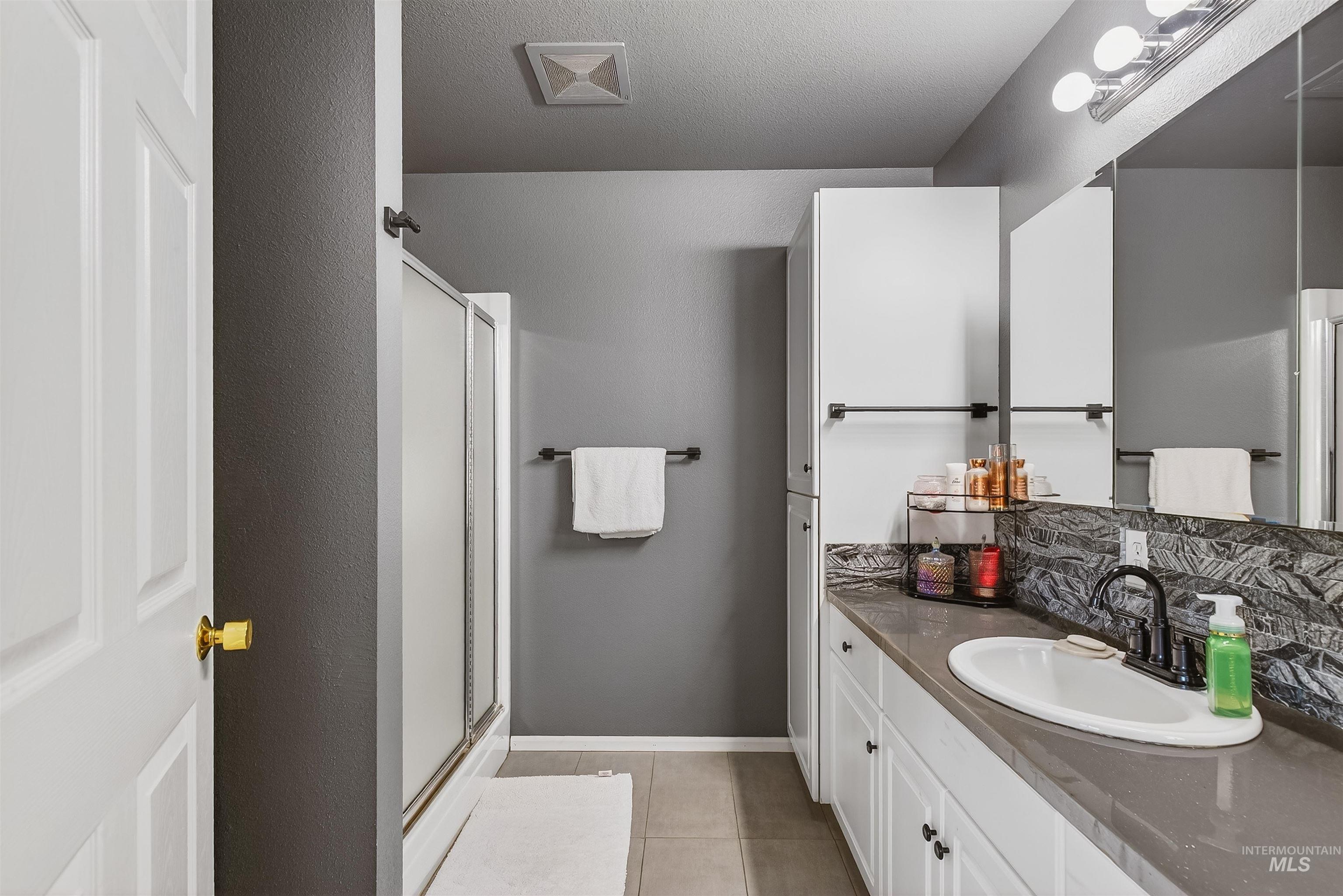 822 15th Avenue Lewiston, ID 83501 - Photo 27 of 44 Full bathroom featuring vanity, a shower stall, light tile patterned flooring, a textured ceiling, and tasteful backsplash