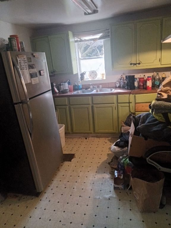 3208 East 16th Street Austin, TX 78721 - Photo 3 of 5 Kitchen featuring a sink, green cabinetry, light floors, and freestanding refrigerator