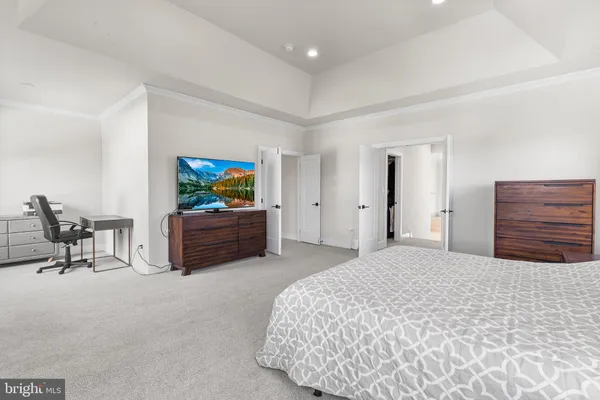 a bedroom with a bed a chair and potted plant on the dresser