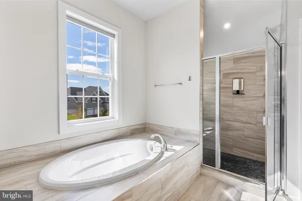 a bathroom with a tub a window and a shower