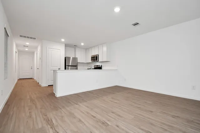 a view of kitchen with kitchen island wooden floor center island and stainless steel appliances
