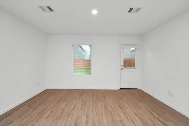 a view of empty room with wooden floor and fan