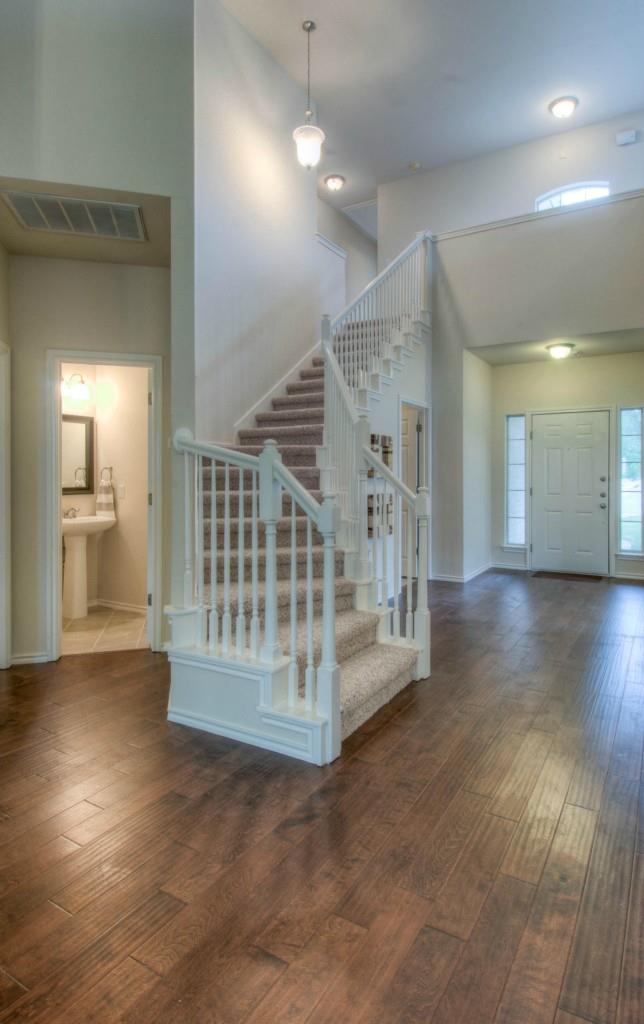 14813 Jacks Pond Road Austin, TX 78728 - Photo 16 of 29 Two-story entry foyer featuring wood-finish flooring, a carpeted staircase with white balusters, and a pendant light fixture