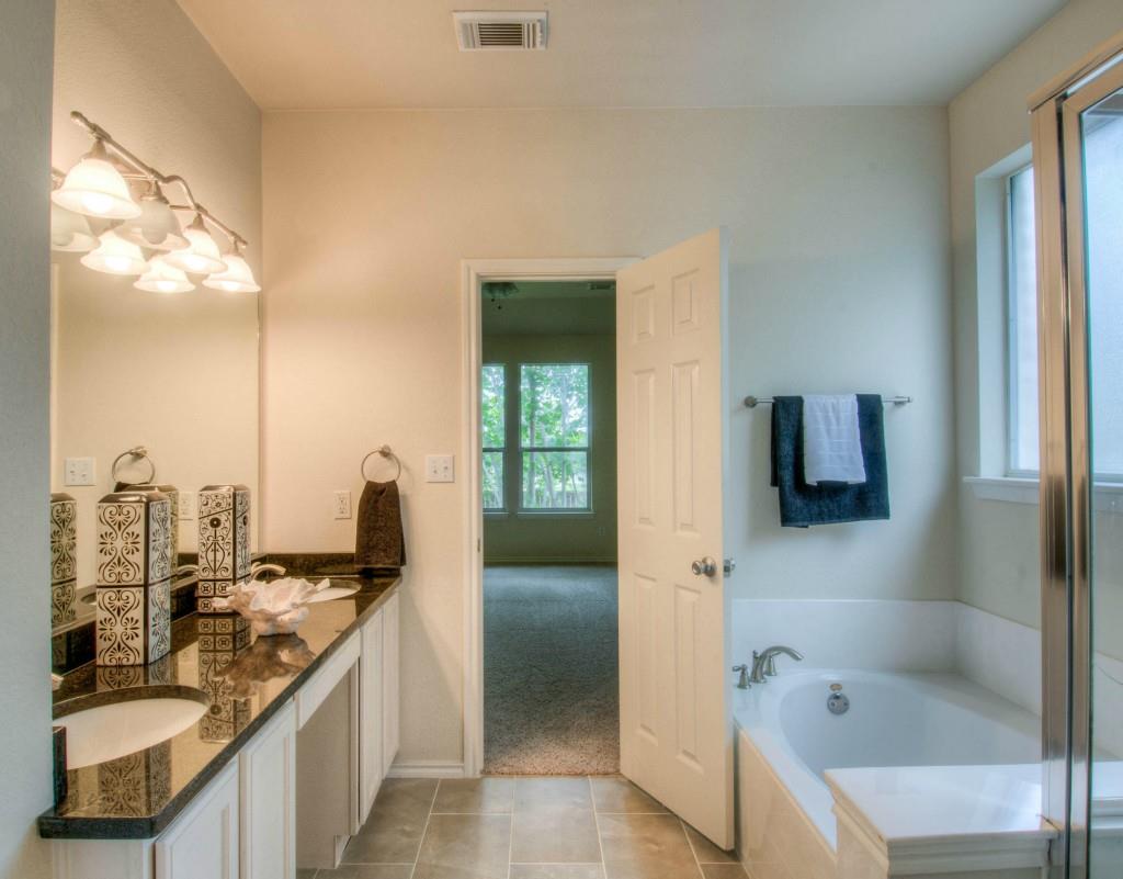 14813 Jacks Pond Road Austin, TX 78728 - Photo 17 of 29 Bathroom featuring a dual vanity with a dark granite-finish countertop, undermount sink, and light wood cabinetry