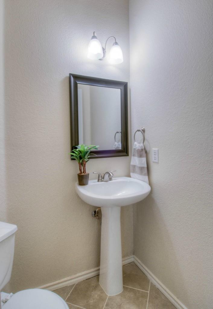 14813 Jacks Pond Road Austin, TX 78728 - Photo 20 of 29 Pedestal sink with chrome fixtures and a framed mirror under a two-light vanity fixture
