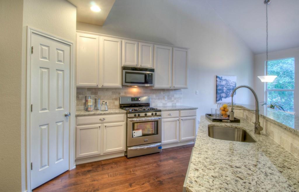 14813 Jacks Pond Road Austin, TX 78728 - Photo 21 of 29 Kitchen featuring granite countertops, stainless steel appliances, white cabinetry, wood-finish flooring, and a large window