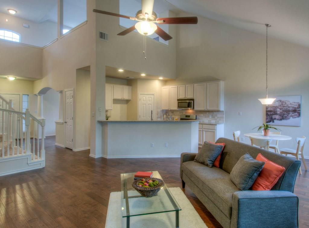 14813 Jacks Pond Road Austin, TX 78728 - Photo 24 of 29 Open-concept living area featuring wood-finish flooring, a vaulted ceiling, and an upper-level architectural feature with an arched window