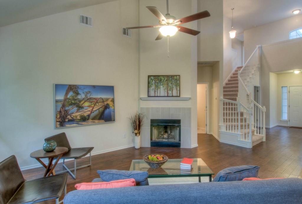 14813 Jacks Pond Road Austin, TX 78728 - Photo 25 of 29 Spacious living area featuring a vaulted ceiling with a ceiling fan, wood-finish flooring, and a tiled fireplace