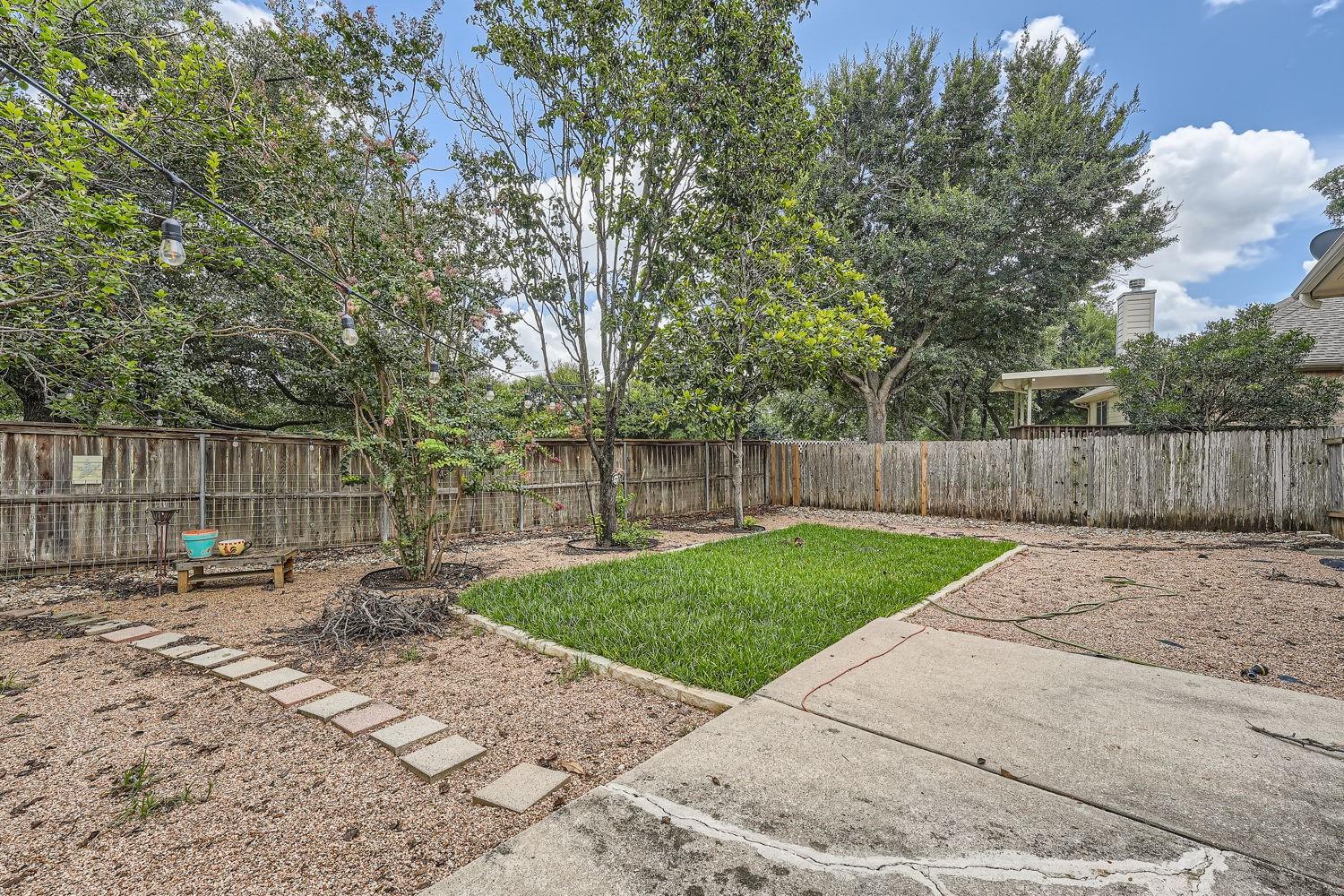 14813 Jacks Pond Road Austin, TX 78728 - Photo 3 of 29 Expansive backyard featuring a central lawn, mature trees, wood privacy fencing, a concrete patio, and stepping stone pathway