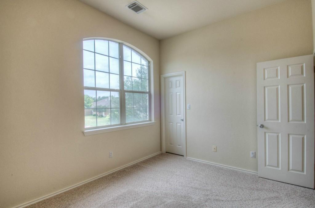14813 Jacks Pond Road Austin, TX 78728 - Photo 10 of 29 Room featuring an arched grid window, two paneled doors, neutral carpet, and vaulted ceilings