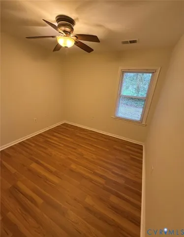 a view of a room with a hanging light and hardwood floor