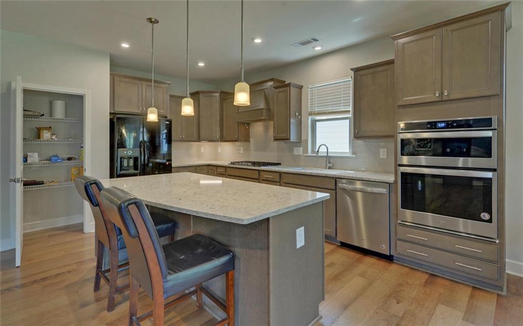 5825 Maple Bluff Way Hoschton, GA 30548 - Photo 15 of 67 a kitchen with granite countertop a stove a sink a dining table and chairs