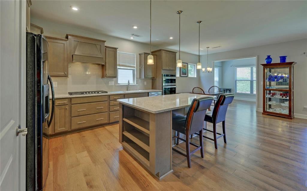5825 Maple Bluff Way Hoschton, GA 30548 - Photo 16 of 67 a kitchen with stainless steel appliances granite countertop a table chairs and a refrigerator