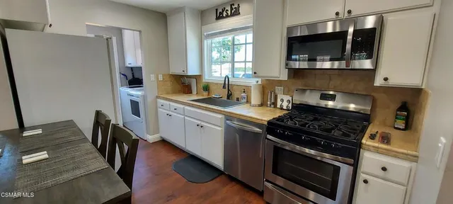 a kitchen with stainless steel appliances a stove microwave and sink