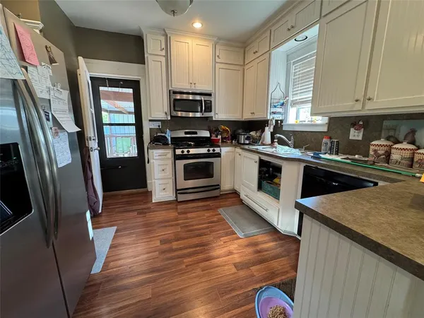 a kitchen with stainless steel appliances granite countertop a refrigerator a stove top oven a sink and dishwasher