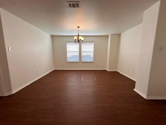 an empty room with wooden floor chandelier and windows