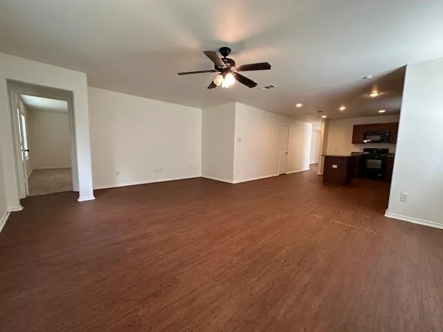 a kitchen with stainless steel appliances granite countertop wooden cabinets a sink a stove a microwave and wooden floors