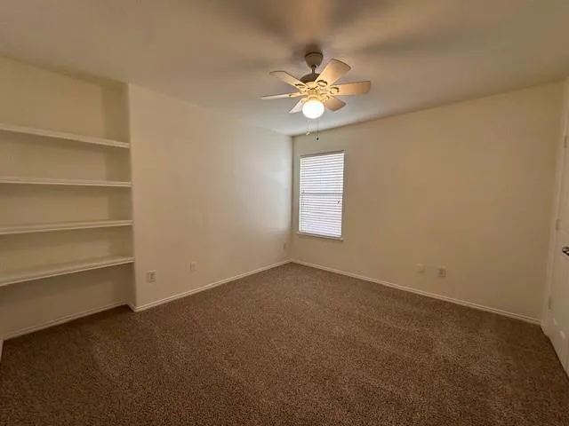 an empty room with a chandelier fan and windows