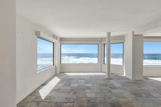 a view of an empty room with a window and a kitchen