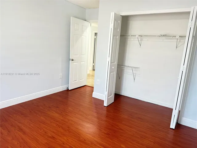 an empty room with wooden floor chandelier fan and windows