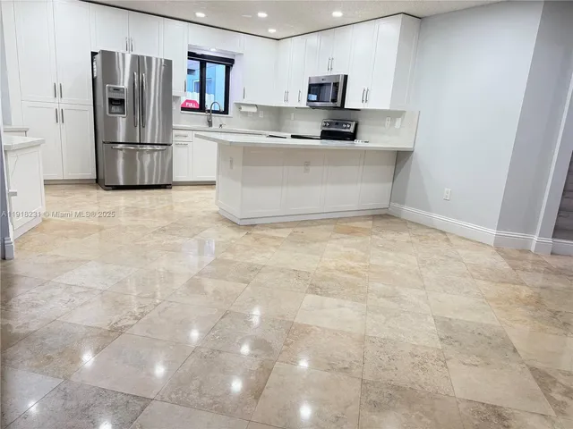 a kitchen with stainless steel appliances granite countertop a refrigerator and a sink
