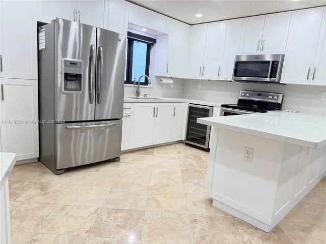 a kitchen with stainless steel appliances granite countertop a refrigerator sink and microwave