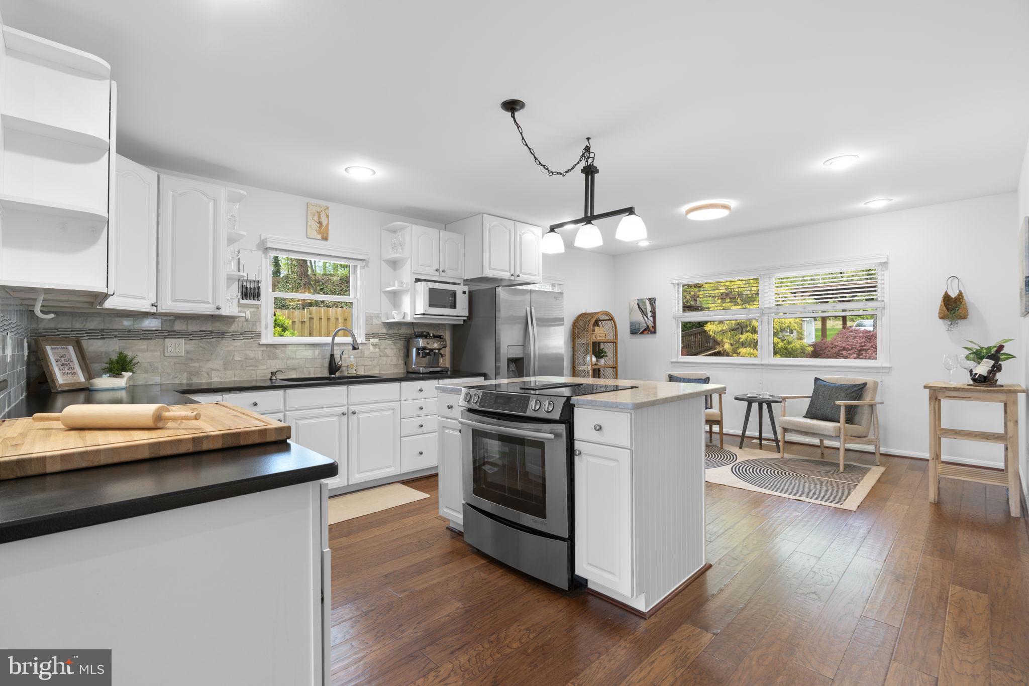 25 Leeland Road Edgewater, MD 21037 - Photo 6 of 48 a kitchen with stainless steel appliances granite countertop wooden floors a stove a white table and chairs