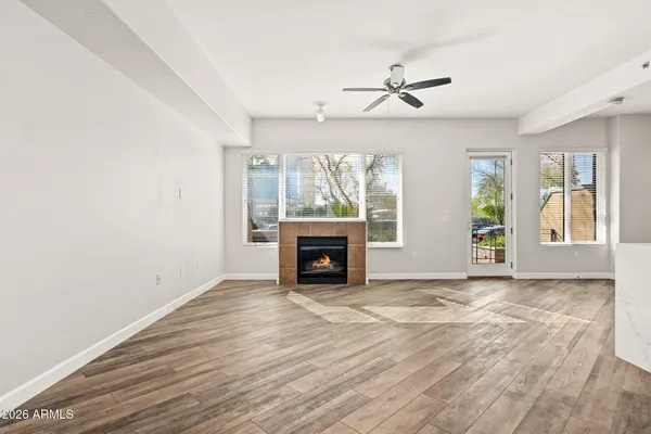 an empty room with windows fireplace and wooden floor