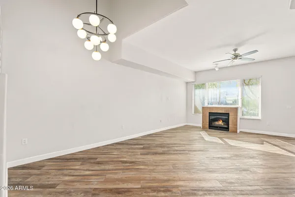 an empty room with fireplace chandelier and windows