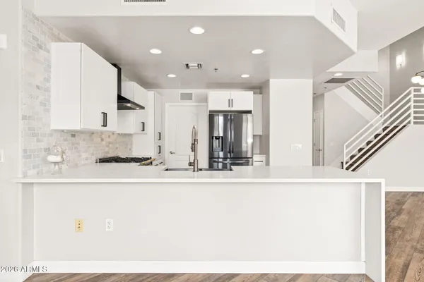 a large white kitchen with kitchen island granite countertop a sink and a refrigerator