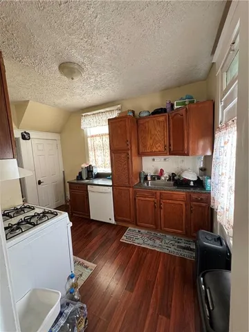 a kitchen with granite countertop a refrigerator stove and wooden floor