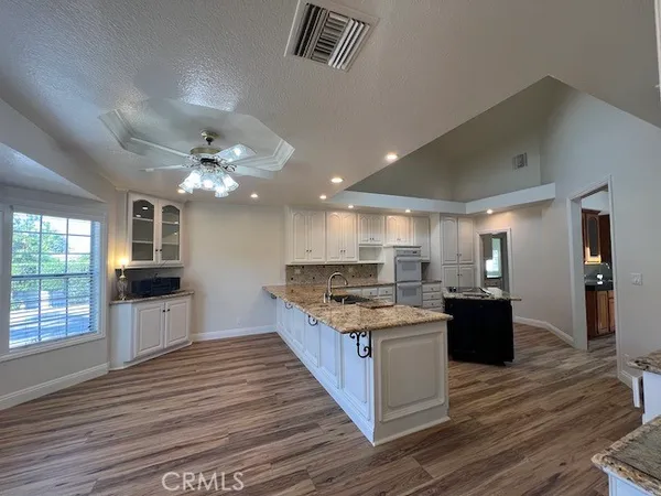 a kitchen with stainless steel appliances granite countertop a stove top oven a sink dishwasher a refrigerator and a dining table with wooden floor