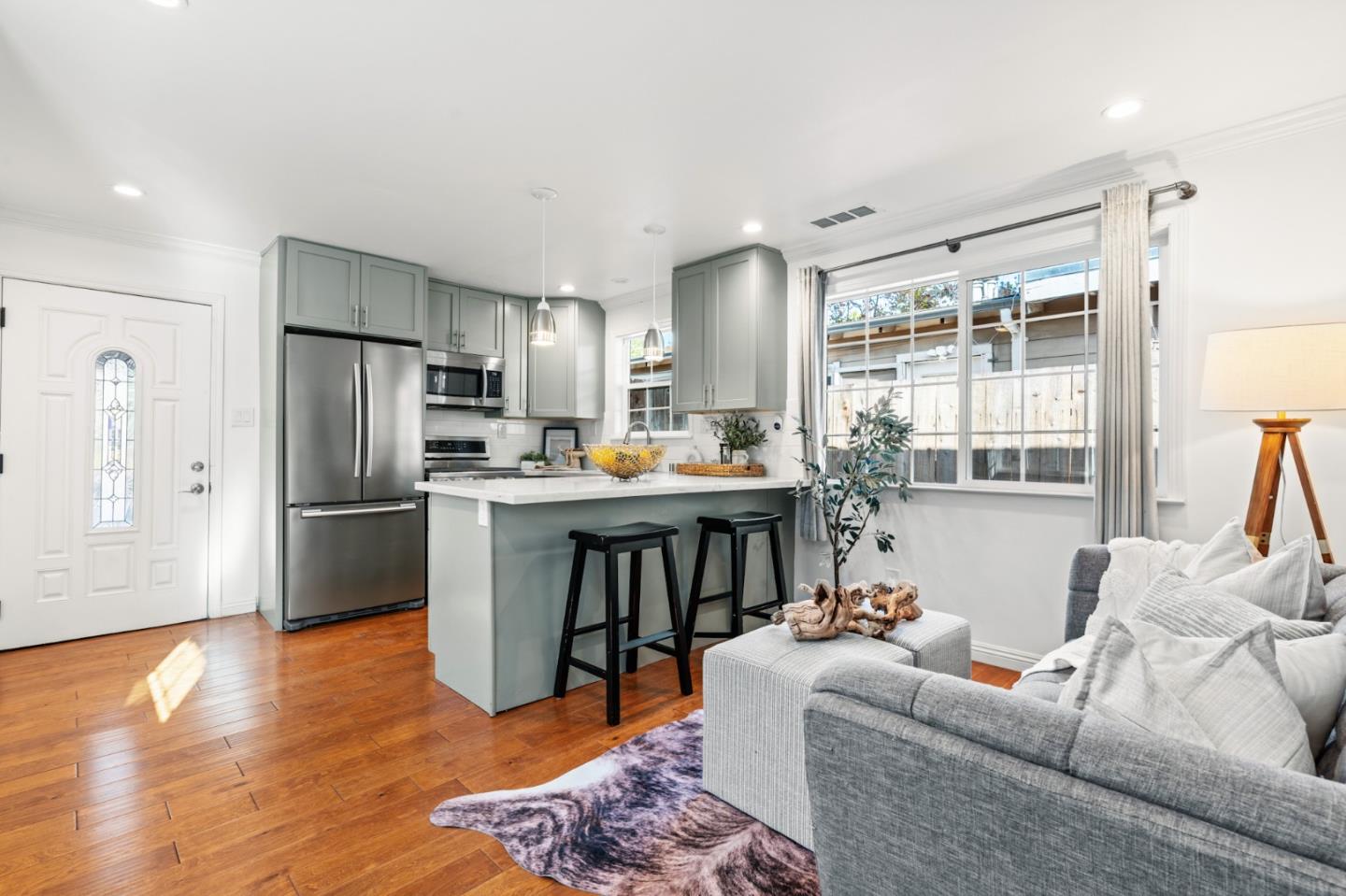 a living room with stainless steel appliances furniture a refrigerator and a kitchen view