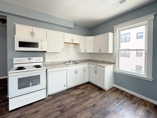 a kitchen with cabinets stainless steel appliances a sink and a window