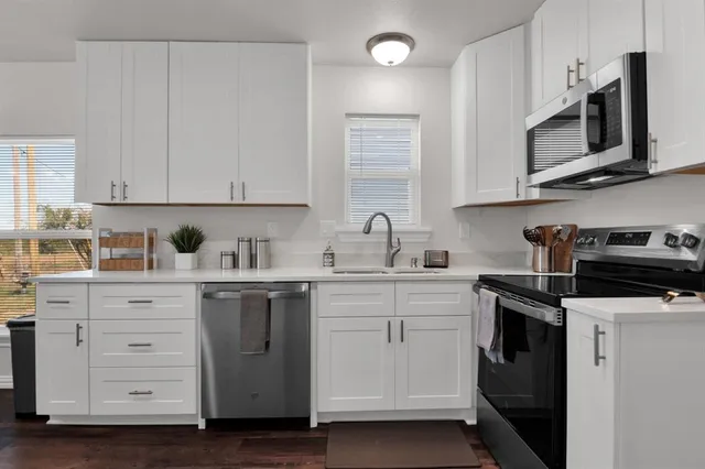 a kitchen with stainless steel appliances granite countertop white cabinets a sink and dishwasher