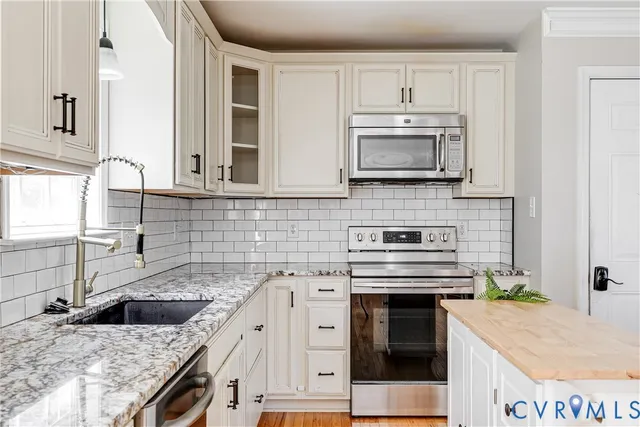 a kitchen with granite countertop a sink stainless steel appliances and white cabinets