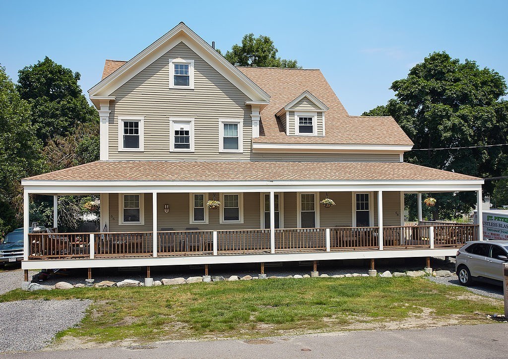 a view of a white house with large windows and a yard with swimming pool and porch