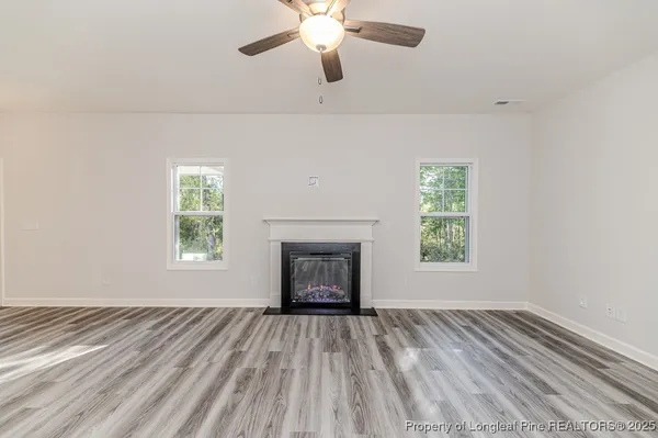 a view of an empty room with wooden floor fireplace and a window