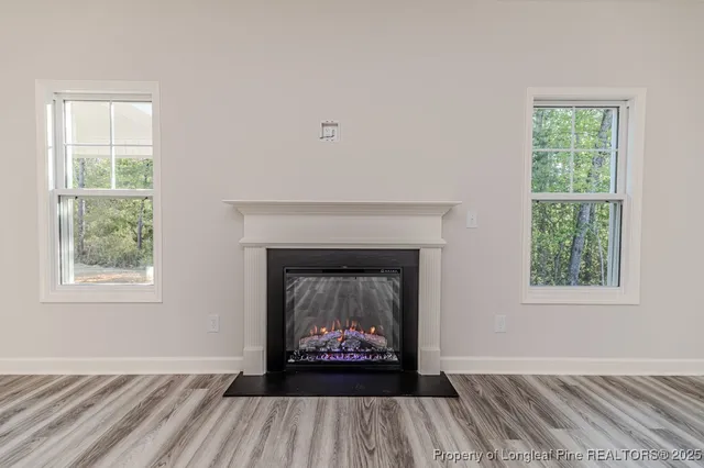 an empty room with windows and fireplace