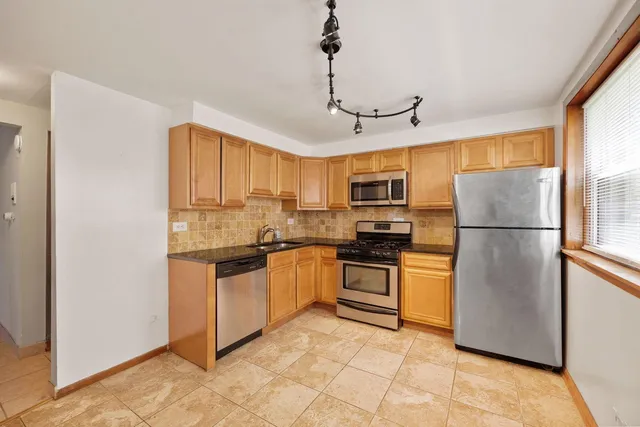 a kitchen with stainless steel appliances granite countertop a refrigerator a stove top oven a sink and cabinets