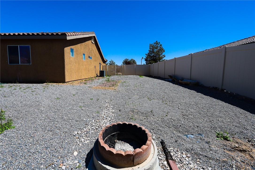 6472 Centennial Road Pahrump, NV 89048 - Photo 19 of 29 A spacious backyard awaits, featuring a fire pit and surrounded by fencing for private enjoyment.