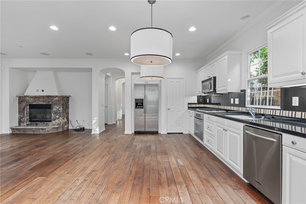 55 Bower Tree Irvine, CA 92603 - Photo 6 of 32 a large kitchen with stainless steel appliances granite countertop a stove a sink dishwasher and a fireplace with wooden floor