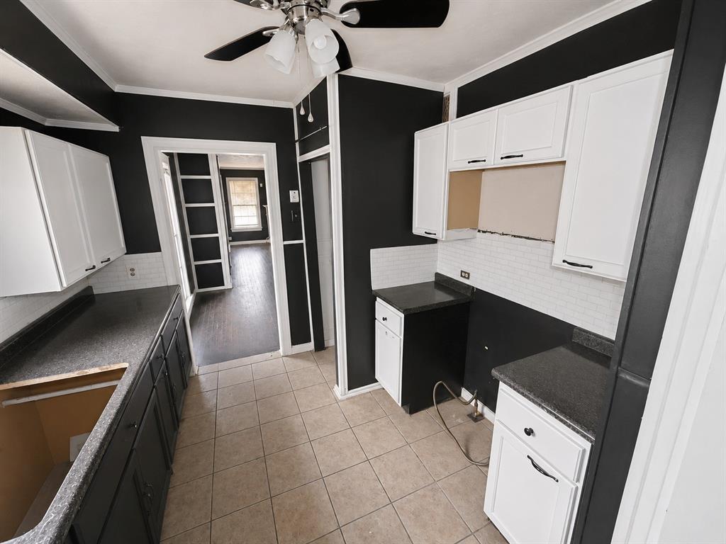 1010 Winters Street Dallas, TX 75216 - Photo 10 of 20 Kitchen featuring light-toned tile flooring, contrasting dark and white cabinetry, dark speckled countertops, and a white subway tile backsplash