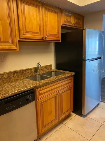 a kitchen with granite countertop a refrigerator and a sink