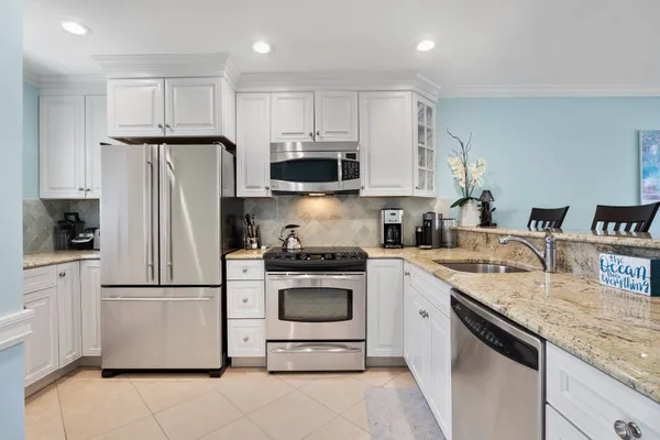 a kitchen with granite countertop white cabinets and stainless steel appliances