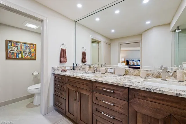 a bathroom with a granite countertop double vanity sink a mirror and a toilet