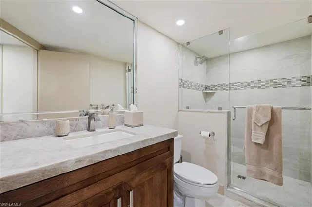a bathroom with a granite countertop sink a toilet a mirror and shower